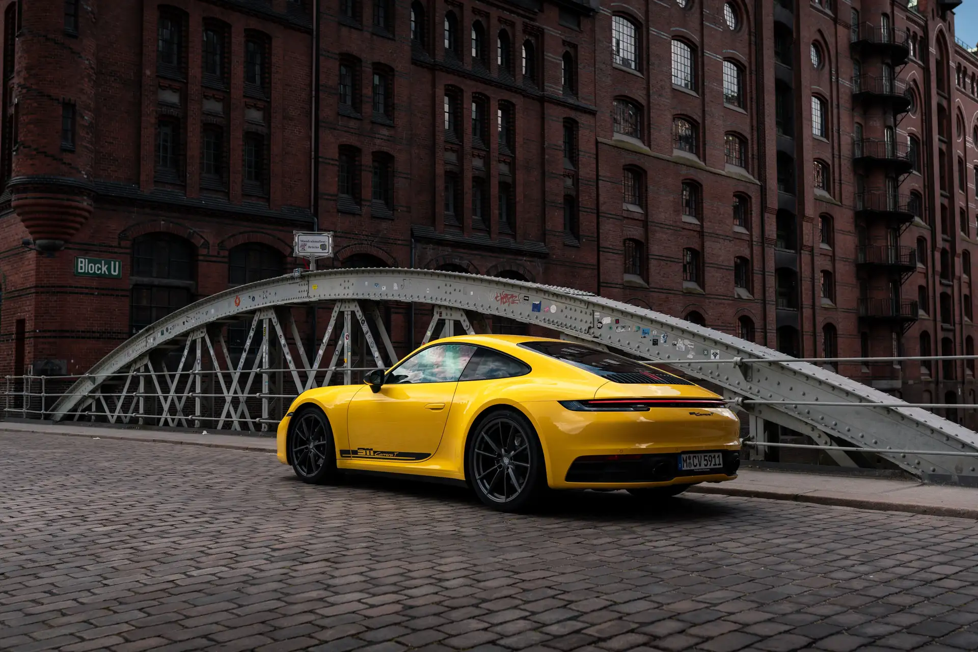 Unser gelber Porsche 911 Carrera von hinten zu sehen auf einer Brücke in Hamburg.